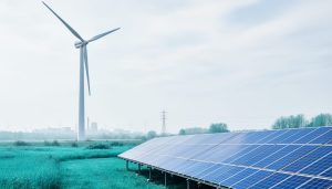 Wind turbine and solar panels with transmission lines in the background, shown in a clean renewable energy landscape under soft daylight.